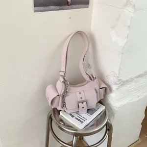 Detail of light pink shoulder bag featuring side pockets and a silver heart pendant