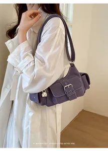 Detail of dark purple retro shoulder bag featuring metal buckle pockets and gold pendant