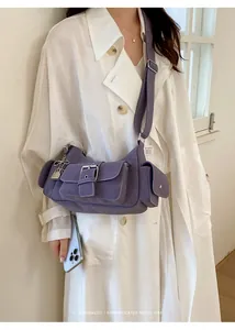 Detail of purple multi-pocket crossbody bag with vintage buckle straps and textured finish