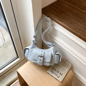 Detail view of a light blue multi-pocket shoulder bag placed on a wooden stool