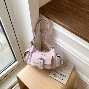 Close-up of pink leather shoulder bag with metallic silver buckles and utility pockets