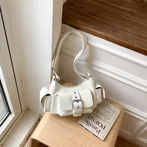Detail view of cream shoulder bag with multi-pocket design and large metal buckle