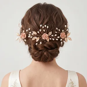 Dettaglio acconciatura sposa con rose rosa, foglie dorate e perle su capelli raccolti
