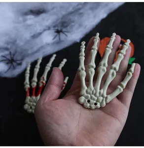 Realistic Halloween plastic skeleton hand bone prop held against festive spooky background