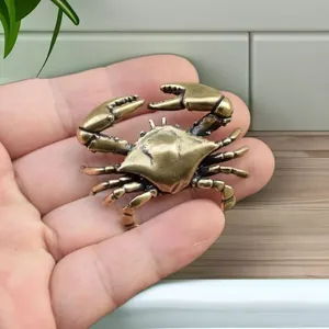 Close-up of vintage bronze crab figurine held in hand showing realistic texture details