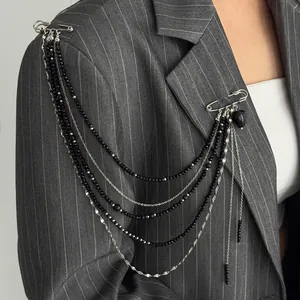 Detail of punk style multi-layer chain brooch with black heart pendant on a grey suit