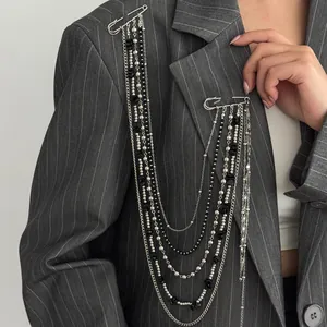 Macro view of multi-layer silver chains and black beads pinned on a grey suit blazer