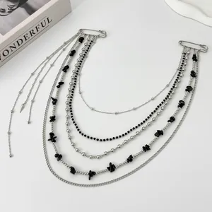 Detail of silver punk chain brooch with black stone beads and multilayered fringes