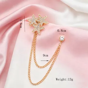 Detailed view of gold star brooch with rhinestones, chain tassels, and measurements