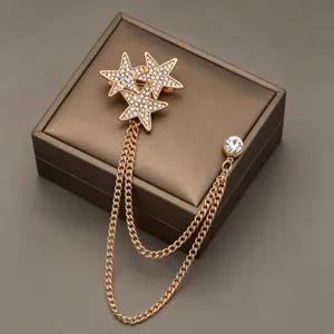 Elegant gold star chain brooch with sparkling rhinestones on a jewelry box surface