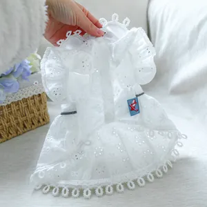 Detail of white lace pet dress showing intricate embroidery and snap button closure