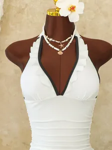 Detail of white halter neck swimsuit with ruffled trim, deep V-neck and ruched texture