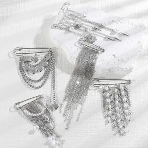 Close-up of silver punk chain brooches with metal tassels, heart charms and pearls