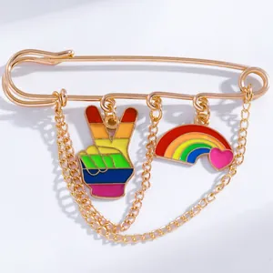 Detail of gold safety pin brooch featuring rainbow peace sign and heart charms
