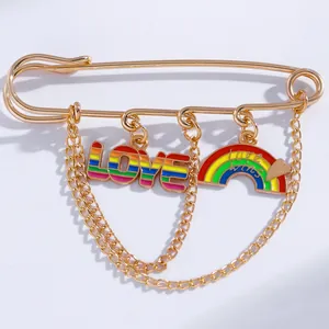 Detail of gold chain brooch featuring rainbow LOVE charms and Love Wins pendant