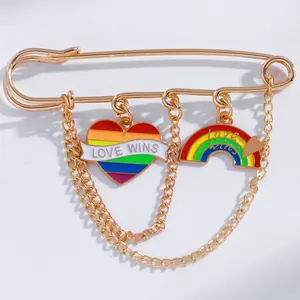 Close-up of golden punk pin brooch with rainbow heart and Love Wins charms