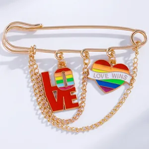 Detailed close-up of golden brooch with LOVE WINS rainbow heart and double chain links