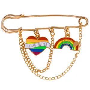 Detail of gold safety pin brooch with Love Wins rainbow heart and hanging chains