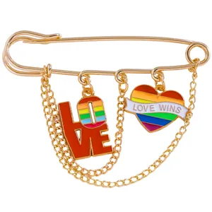 Close-up of gold chain brooch with Love Wins heart enamel charm and rainbow letters