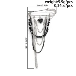 Detail of silver safety pin brooch with black heart gem and beaded tassel fringe