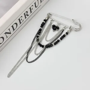 Close-up of heart gemstone pendant and silver layered bead chains on safety pin brooch