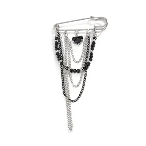 Detail of silver safety pin brooch with black heart pendant and tassel chains