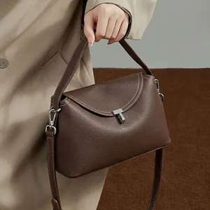 Macro detail of brown litchi leather handbag with silver T-shaped metal buckle clasp