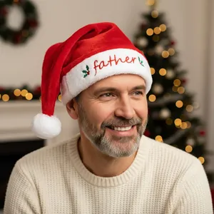 Detail of red plush Santa hat featuring Father embroidery and holly berry decoration