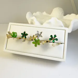 Detalle de set de anillos de flores doradas con cristales verdes y perlas finas