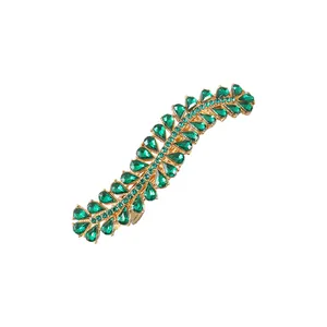 Close-up of S-shaped gold alloy hair clip with emerald green rhinestones detail
