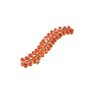 Detailed close-up of a golden spring hair clip with vibrant red rhinestones