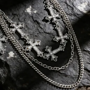 Dettaglio di ciondoli a croce vintage in argento a strati con trame metalliche gotiche
