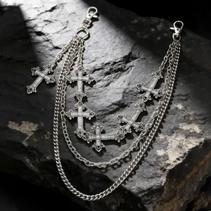 Dettaglio di catene d'argento multistrato vintage con pendenti a croce gotica su roccia