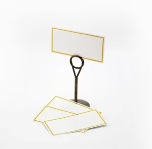 Macro shot of bronze metal place card holder with elegant gold-bordered white seat cards
