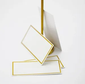 Close-up of elegant white wedding place cards with gold foil border and metal stand
