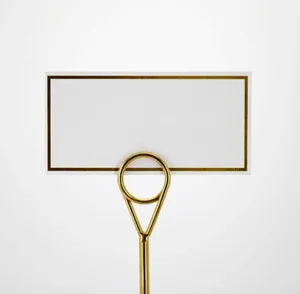 Detail of elegant gold metal place card holder with white card for wedding table decor