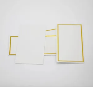 Close-up of white place cards with elegant gold foil borders for wedding guest seating