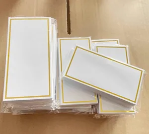 Detail view of bulk white place cards with elegant gold borders in clear packaging
