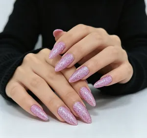 Détail de faux ongles stiletto longs avec paillettes roses et une finition scintillante