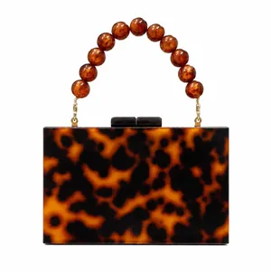Elegant tortoiseshell acrylic clutch bag with amber beaded handle and gold hardware