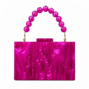 Detail of fuchsia acrylic evening clutch with beaded handle and marble texture finish