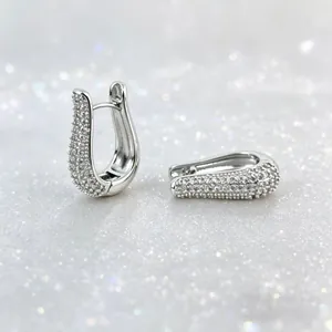 Detail of silver plated U-shaped huggie earrings with pavé set micro cubic zirconia stones