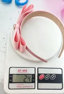 Vue détaillée du serre-tête rose à double nœud avec strass sur une balance rose