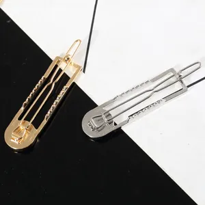Detail of geometric hollow hair clips in gold and silver finish with turquoise accents