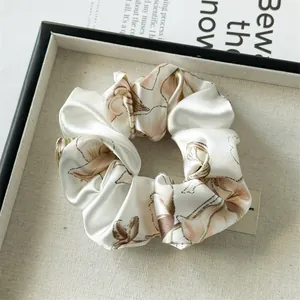 Floral print cream satin scrunchie with soft pink flowers on an elegant tray