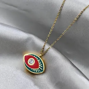 Detail of gold evil eye pendant with red and green enamel and sparkling zircon