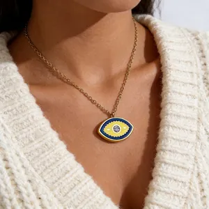 Close-up of golden Evil Eye pendant with blue enamel and crystal on a knit sweater