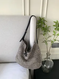 Detail of hand-woven straw tote with black leather strap and ox horn buckle closure