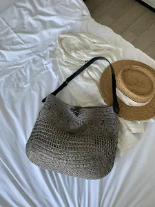 Detailed top view of large grey woven beach bag with hollow texture and black straps