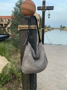 Detail of hand-woven hollow straw beach tote with leather strap and horn button closure